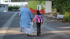 Eine Mutter begleitet ihre Tochter zu Schulbeginn zu Fuß zur Schule