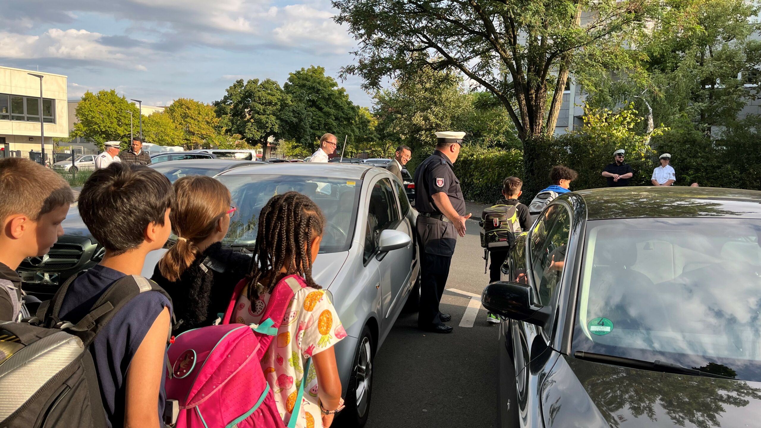 Kinder erhalten von der Städtischen Verkehrspolizei wichtige Hinweise, wie sie die Straße sicher überqueren.