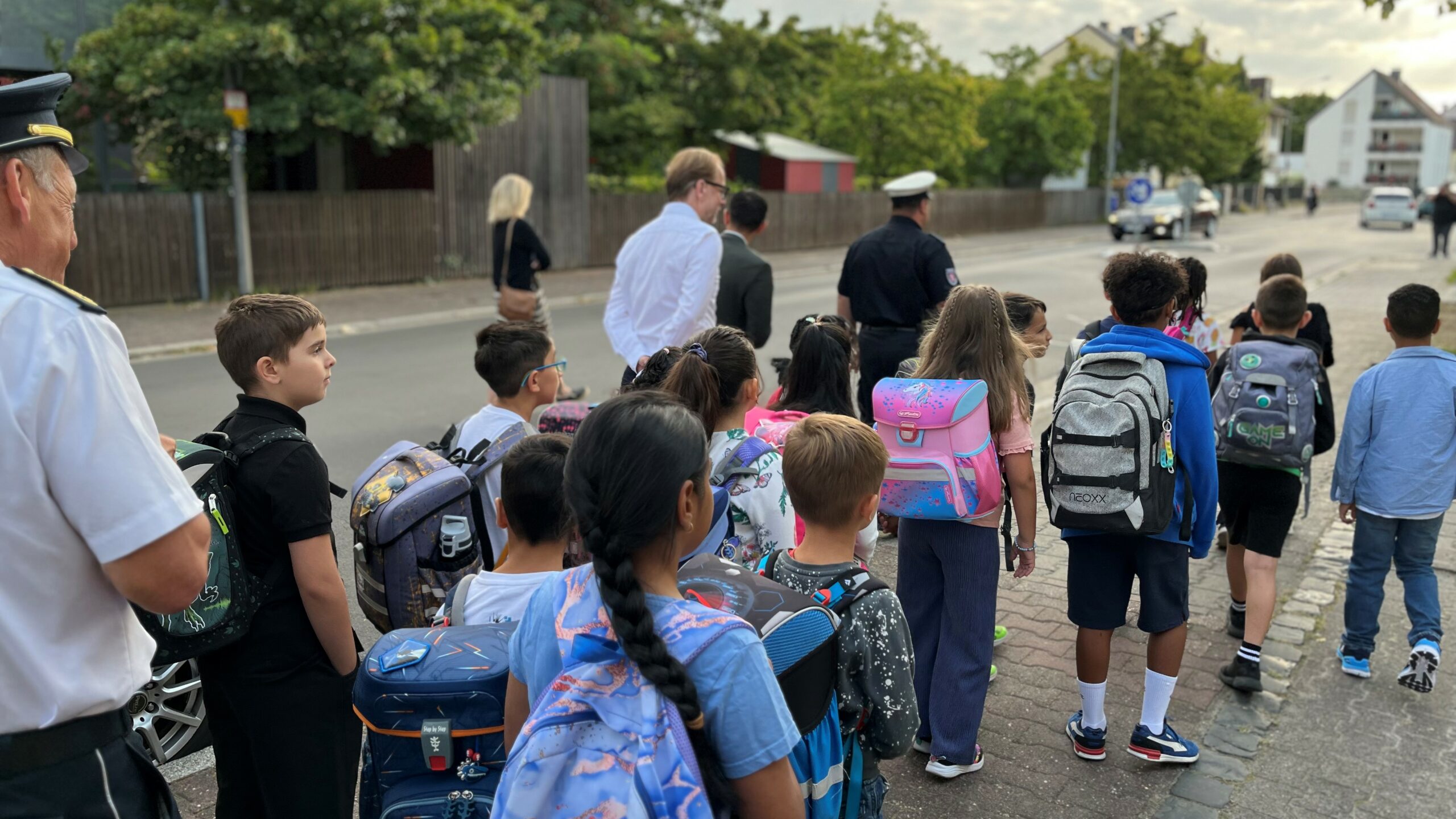 Grundschulkinder laufen den Schulweg zur Freiligrathschule Fechenheim gemeinsam mit behördlichen Vertreterinnen und Vertretern.